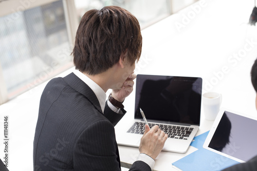 Two young businessman, looking at a laptop in the office