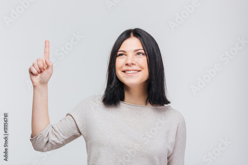 Portrait of a pretty young brunette girl pointing finger up