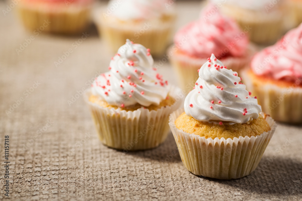 Vanilla cupcakes with white and pink cream, concrete background, selective focus, close up
