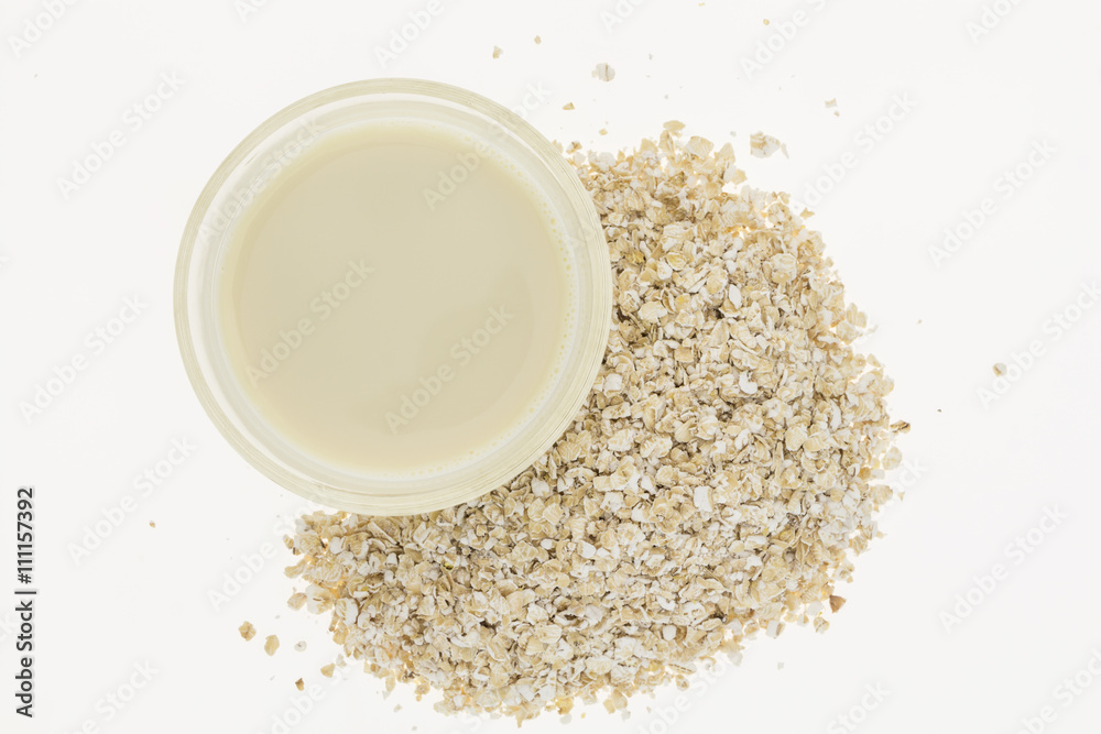 Glass of homemade oat milk and oatmeal, on white background Glass of homemade oat milk and oatmeal, on white background