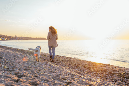 young beautiful woman playing with labrador dog on the beach