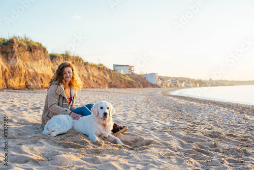young beautiful woman playing with labrador dog on the beach