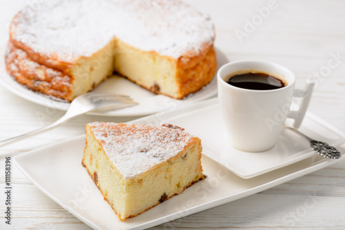 Cheesecake slice and cup of coffee on wooden background.