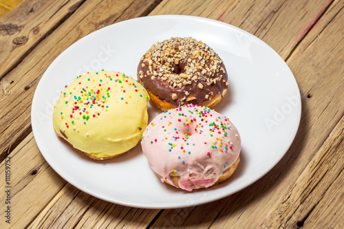 Delicious donuts with icing on plate 