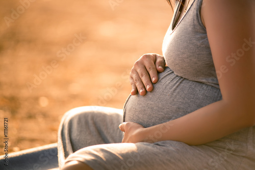 Pregnant woman relaxing lakeside sunset background