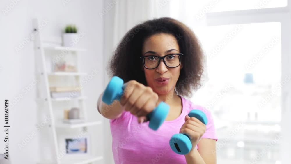 african woman exercising with dumbbells at home