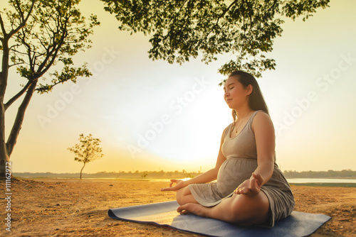 Pregnant woman silhouette yoga is sunset