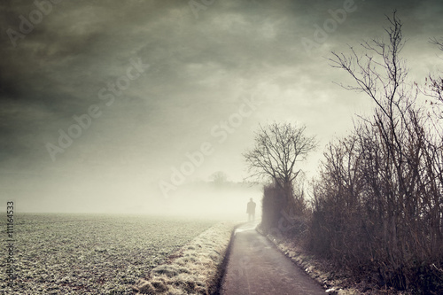 Gernany, North Rhine-Westphalia, Silhouette of a man standing on foggy country road