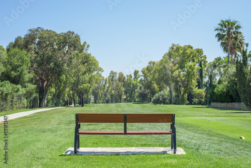 Golf course bench with trees in the background