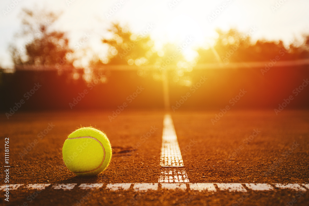 Tennis ball on clay court at suset