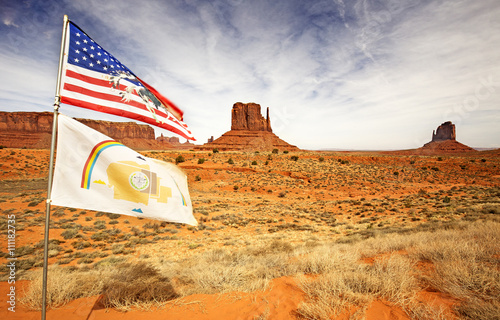 american and navajo flags waving in monument valley photo