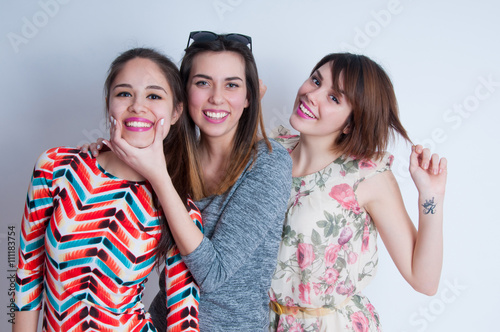 Studio lifestyle portrait of three best friends hipster girls wearing stylish bright dresses, going crazy and having great time together