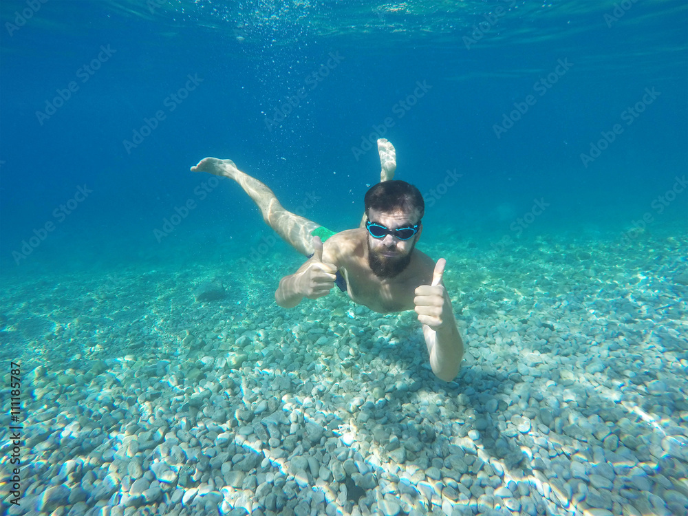 Beard man with mask diving in a blue clean water