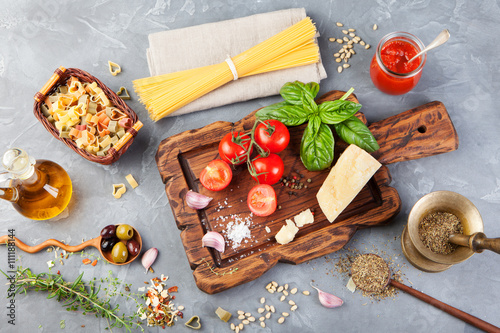 Italian food background with vine tomatoes, basil, spaghetti, olives, parmesan, olive oil, garlic
