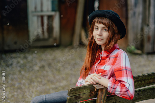 Teen girl in a red plaid shirt walking in the yard, where the cherry blossom trees