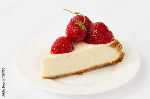 Slice cheesecake with fresh strawberries on white plate