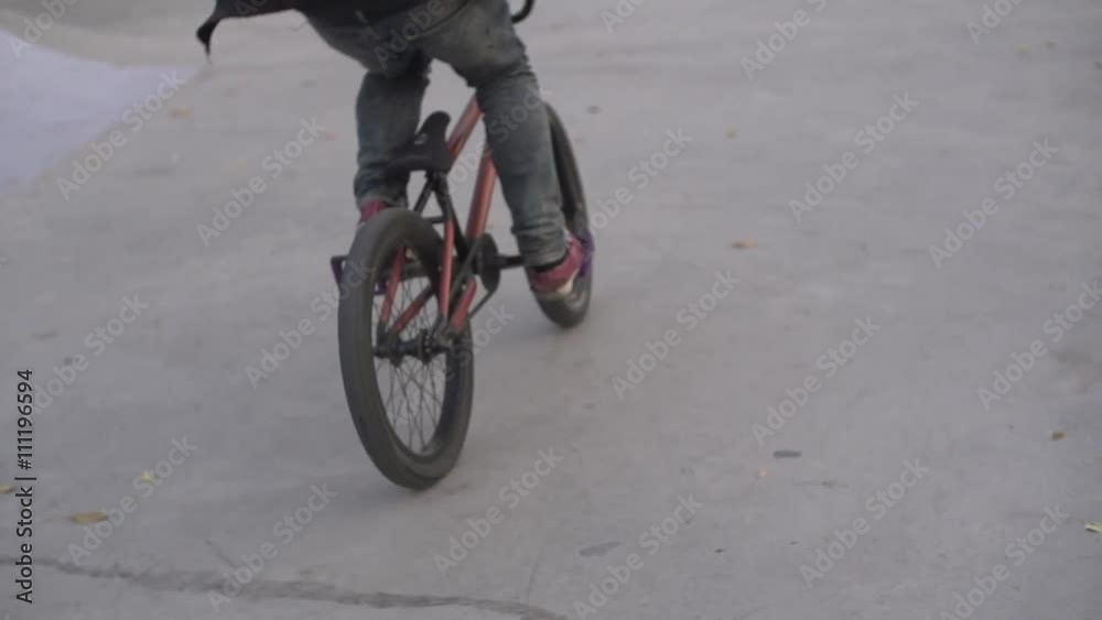 Young boy rides his bmx bike in park in summer. 