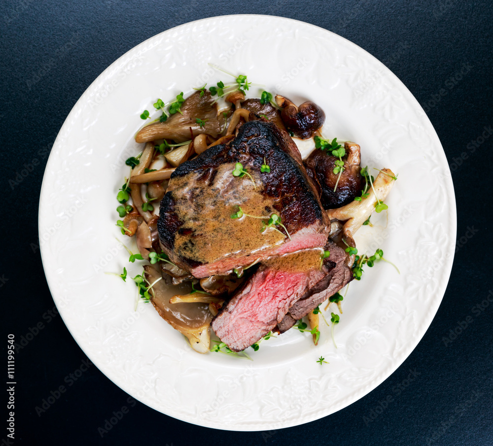 Tasty Beef Mignon steak with mushrooms and herbs on plate. Tasty Beef Mignon steak with mushrooms and herbs on plate.