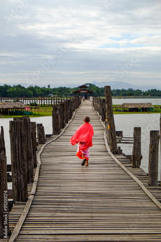 Amarapura, Myanmar - 28 June, 2015: Young monk walks on wooden U