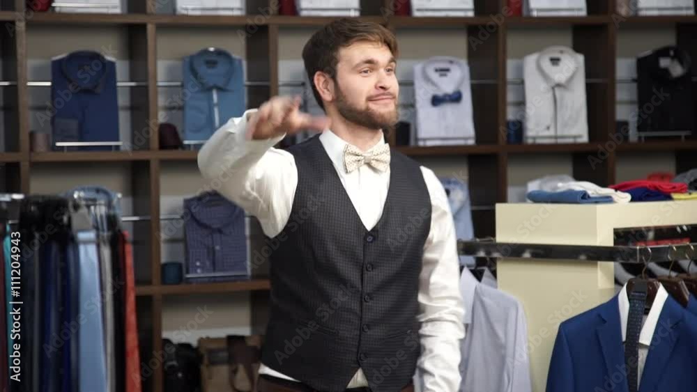 Young attractive man with a beard, dressed in a business suit, dancing in a men's clothing store.