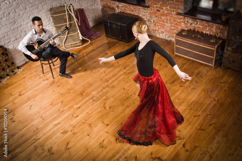Young woman dancing flamenco and a man playing the guitar