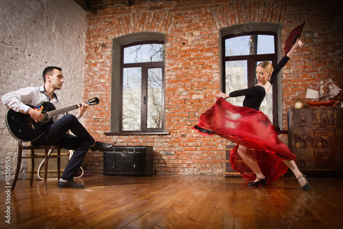 Young woman dancing flamenco and a man playing the guitar
