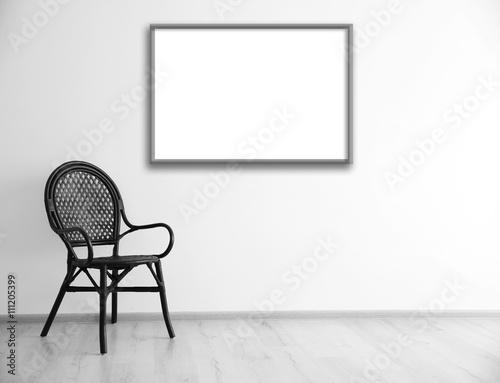 Fototapeta Naklejka Na Ścianę i Meble -  Black chair and empty picture frame on wall background