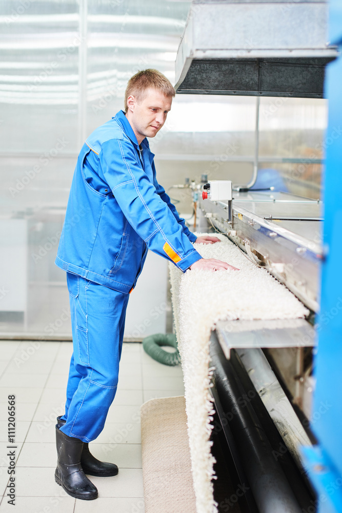 Laundry worker in the process of working on the automatic machine for drying carpets Laundry worker in the process of working on the automatic machine for drying carpets
