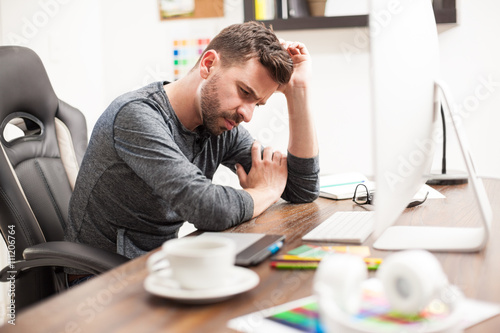 Thoughtful man leaning on his desk at work
