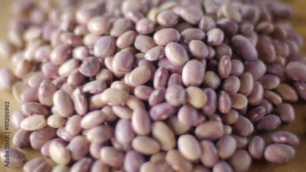 Dried pinto beans rotating on a wooden cutting board