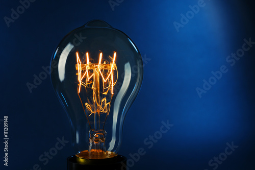Illuminated light bulb on dark blue background
