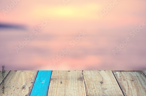 Blur tropical sunset beach with old empty wood table background.