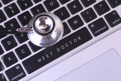 close up of stethoscope and MEET DOCTOR written on laptop keyboa