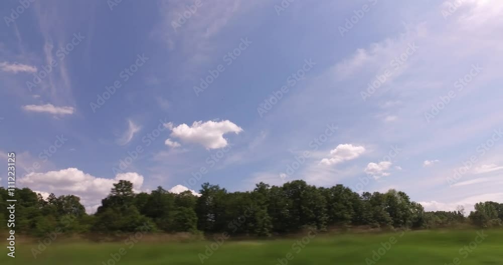 Passing car near a village with beautiful nature, forests, fields, Plain Landscape Green Meadow, beautiful white clouds on a wonderful blue sky Passing car near a village with beautiful nature, forests, fields, Plain Landscape Green Meadow, beautiful white clouds on a wonderful blue sky