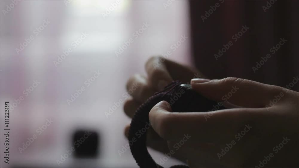 Hands sewing ornaments on handmade bracelet