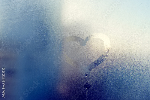 Фотография Love heart drawing on glass. The window is fogged up with drops