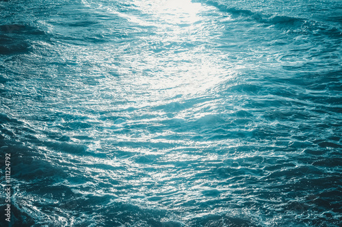 Blue waves of the sea and foam background, reflections of sun light