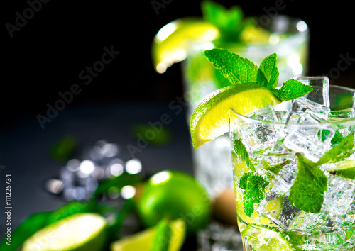 Mojito cocktail on a table. Summer cocktail with rum, lime, mint, ice cubes and brown sugar