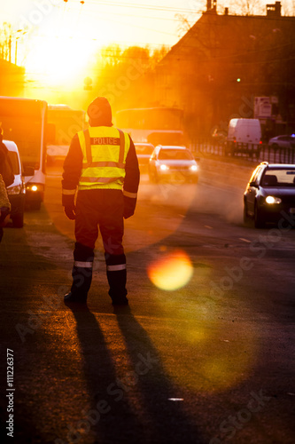 Police officer observe busy traffic. Sunset light with sun flare