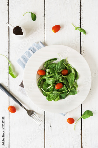Rocket salad with cherry tomatoes on white wooden background