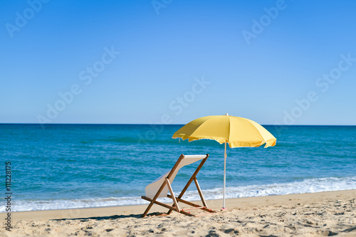 Back View Of Deckchair  Sun Lounger Under Umbrella On Sand Beach. 