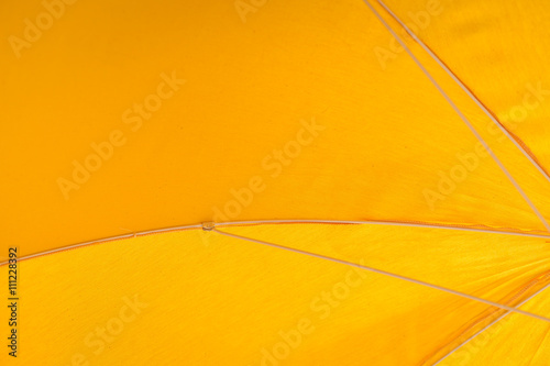 Closeup on yellow umbrella see-through blue sky and sun. Vacation holiday 