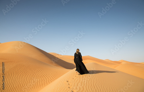 A woman in abaya in sanddunes in Liwa Desert, Aby Dhabi, UAE