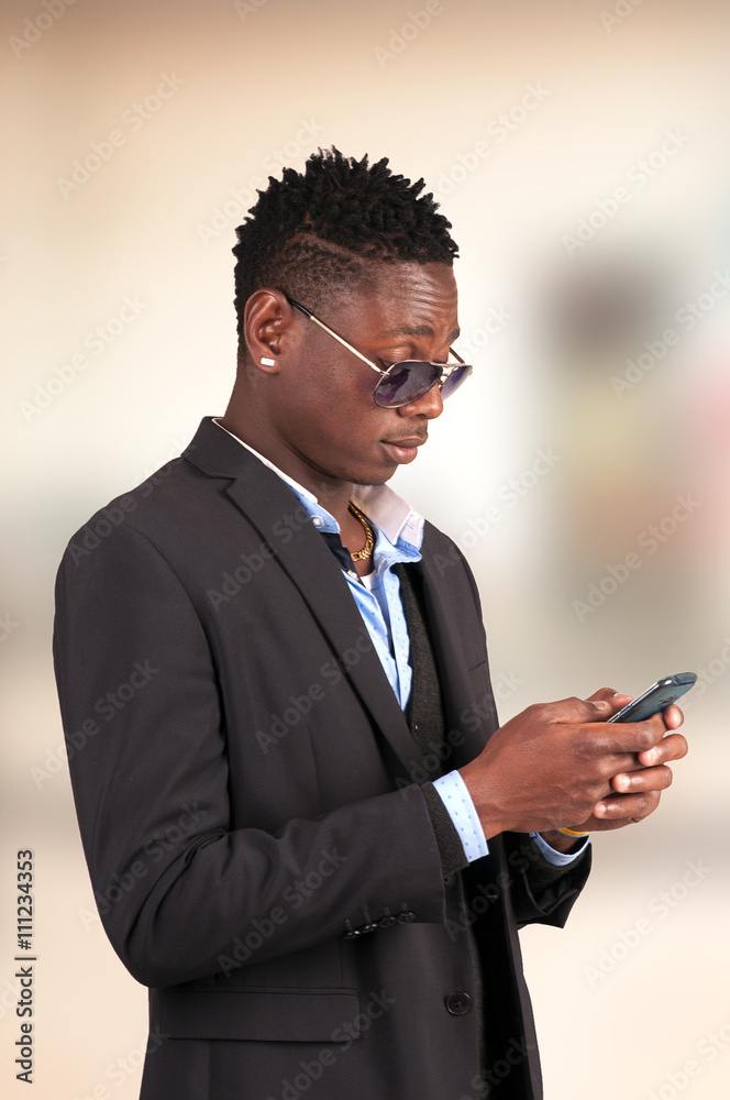 Young smart african american man sending message with mobile phone at airport lounge Young smart african american man sending message with mobile phone at airport lounge