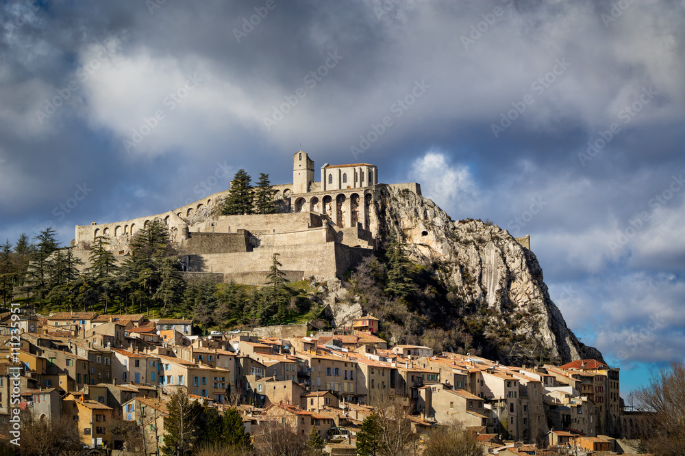 Sisteron Citadel, fortifications and rooftops with clouds. Southern Alps, France
