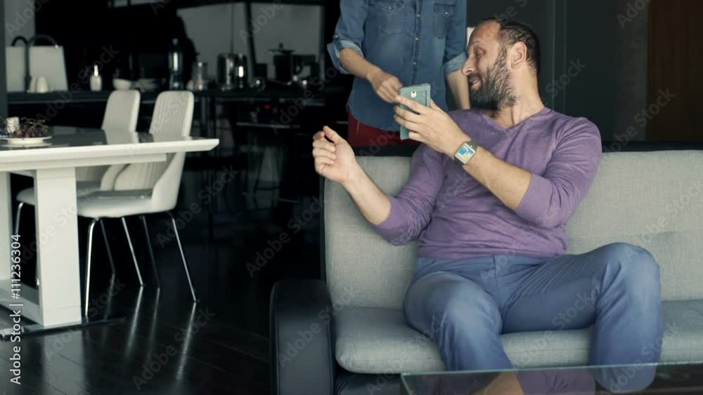 Young, happy couple browsing photos on smartphone sitting on sofa at home
Young, happy couple browsing photos on smartphone sitting on sofa at home