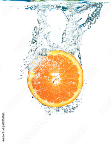 Fototapeta Naklejka Na Ścianę i Meble -  fetta di arancia che cade in acqua