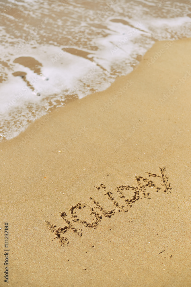Top view on inscription Holiday on sea sand beach with the sun rays against wave foam. vacation concept Top view on inscription Holiday on sea sand beach with the sun rays against wave foam. vacation concept