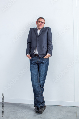 smiling modern entrepreneur shrugging and leaning on the office wall