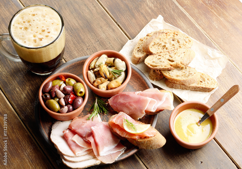 Tapas of salmon, mussels, jamon and olives with beer Tapas of salmon, mussels, jamon and olives with beer